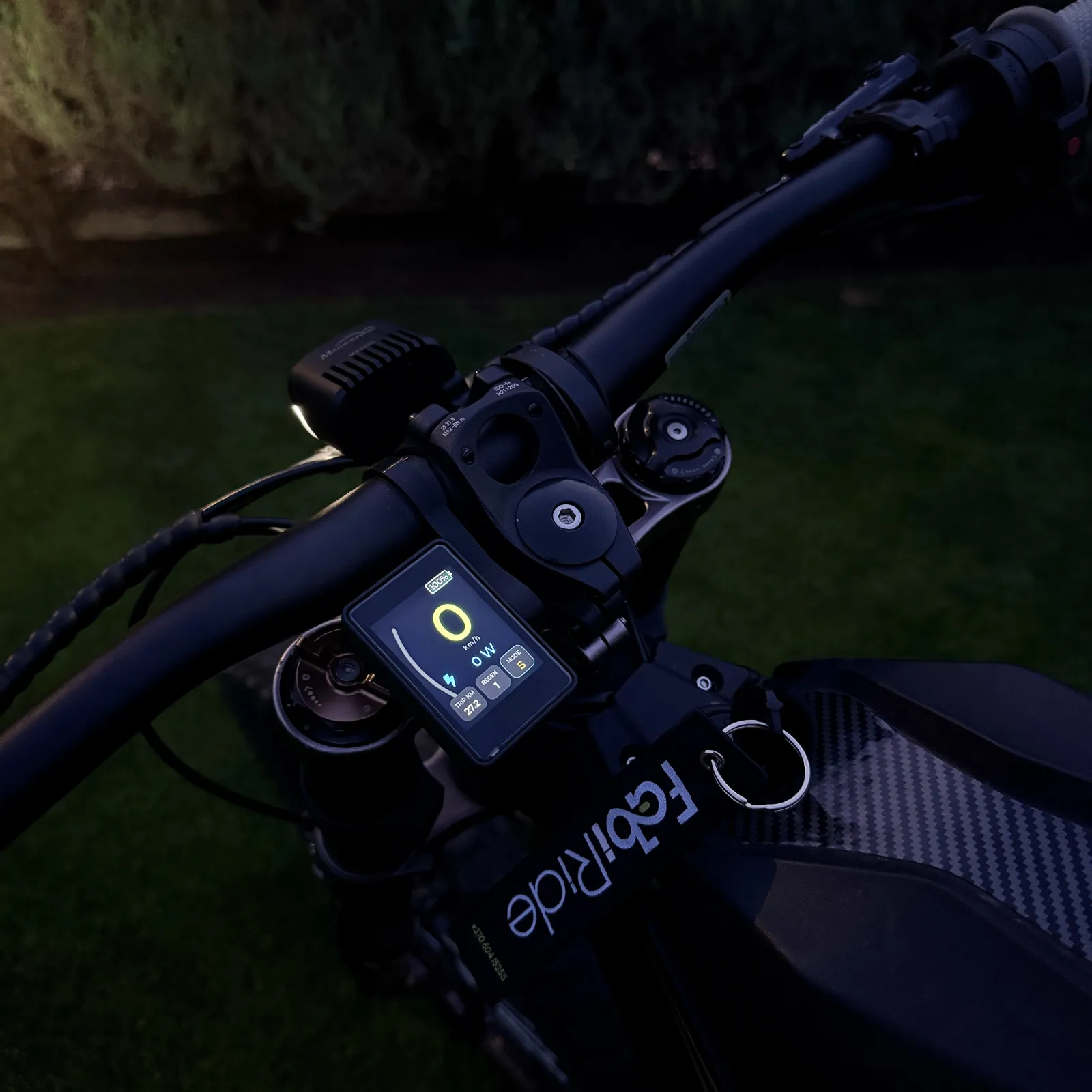 A FabiRide display lit on the handlebars of an electric bike at dusk